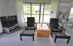 een woonkamer met een tafel en twee stoelen en een televisie bij Liljebo in Vemmenæs