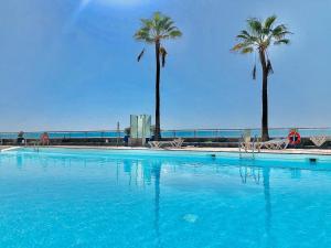 a large swimming pool with palm trees and the ocean at AMADORES BEACH & OCEAN VIEWS in Amadores