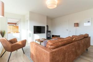 a living room with a large brown couch and two chairs at Diekhuus Büsum in Büsum