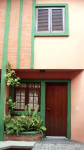 uma casa com uma porta castanha e duas janelas em Sobrado in Village no Guarujá