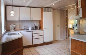 La cuisine est équipée de placards blancs et d'un réfrigérateur blanc. dans l'établissement 2 Bedroom Pet Friendly Home In Vejby, à Vejby