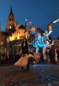 a woman in a dress dancing in front of a building at La Closerie Teranga in Bayeux