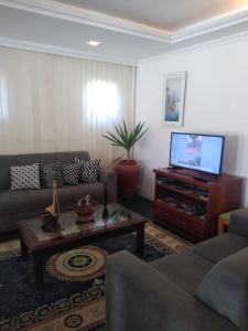 a living room with a couch and a flat screen tv at Hotel Pousada Laje de Itauna in Saquarema