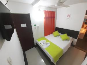 a small room with a bed with green pillows at Hotel Arcoiris Girardot in Girardot