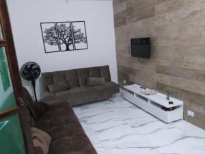 een woonkamer met een bank en een tv bij Casa em Condominio Caragua in Caraguatatuba