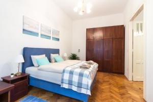 um quarto com uma cama azul e branca e pisos em madeira em Szasz Buda Villa Apartment next to Buda Castle district em Budapeste