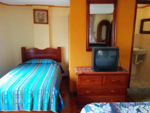 1 dormitorio con cama y vestidor con TV en Hostal Curiñan, en Otavalo