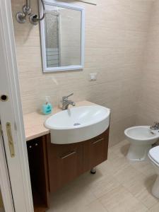 La salle de bains est pourvue d'un lavabo blanc et de toilettes. dans l'établissement Playa Apartment 230 - 230 bis, à Catane