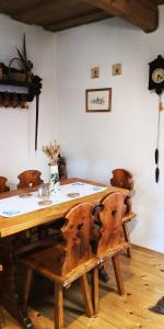 einen Esstisch mit Stühlen und eine Uhr an der Wand in der Unterkunft Drevenica pod Tlstou in Blatnica