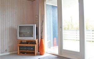 a television sitting on a stand in a room with a window at 3 Bedroom Nice Home In Fan in Fanø