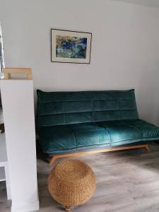 un sofá verde en una sala de estar con taburete en Le Grenier de Gaston, en Thouars-sur-Garonne