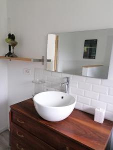 baño con lavabo blanco en una cómoda de madera en Le Grenier de Gaston, en Thouars-sur-Garonne