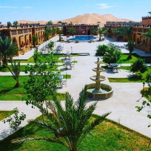a large courtyard with tables and chairs and a fountain at Residence Touristique Merzouga in Merzouga