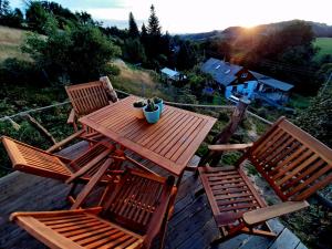 einen Holztisch und Stühle auf einer Terrasse mit Blick auf den Sonnenuntergang in der Unterkunft Individuelle Jurte in der Sächsischen Schweiz in Sebnitz
