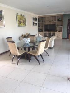 a dining room with a glass table and chairs at Bluewave Lifestyle Villa in Hartbeespoort