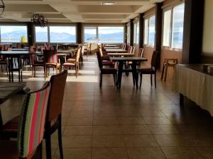 a dining room with tables and chairs and windows at Hotel Las Dunas in El Calafate