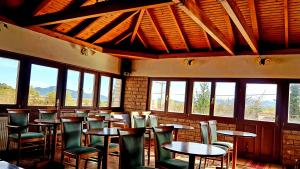 a dining room with tables and chairs and windows at Hotel Odysseas in Kalyvia
