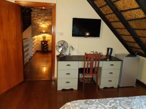 Schlafzimmer mit einem Schreibtisch, einem TV und einem Stuhl in der Unterkunft Little Tree loft 2 in Uitenhage