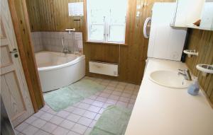 a bathroom with a tub and a sink and a refrigerator at Holiday Home Thadesvej Rømø Iv in Toftum