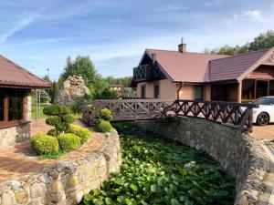 a bridge over a pond in front of a house at Domek nad stawem in Działdowo