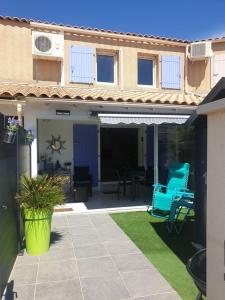 ein Haus mit einer Terrasse mit blauen Stühlen und einem Tisch in der Unterkunft Villa tout confort dans résidence privée avec piscine à 500m de la plage - Climatisation, WIFI, parking in Portiragnes