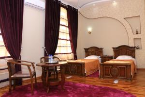 una camera d'albergo con due letti, un tavolo e uno specchio di Luxury Guesthouse a Samarkand