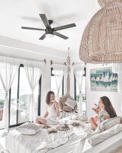 two women sitting on a bed in a room with windows at Icaco Island Village - Adults Only in Isla Mujeres