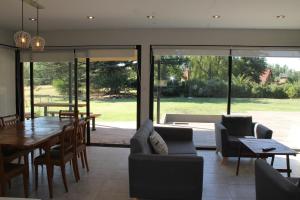 a living room with a table and chairs and glass doors at Casa Cardales MINI PISCINA CLIMATIZADA in Sierra de la Ventana
