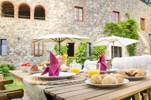uma mesa de madeira com comida e guarda-chuvas em Mas Valentí 1511 em Vall-Llobrega