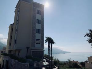 a building with a palm tree in front of the ocean at Ive Lole Ribara 38 in Becici