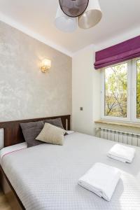 - une chambre avec un lit doté de draps blancs et une fenêtre dans l'établissement Warsaw's Vibes Apartment, à Varsovie