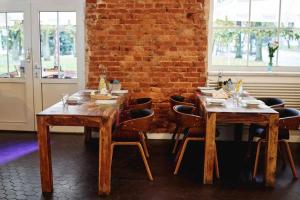 two wooden tables and chairs in a room with a brick wall at Parkova - pokoje hotelowe in Gołdap