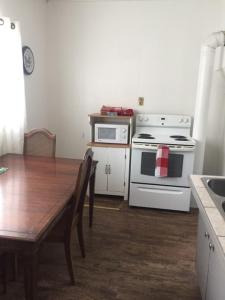 una cocina con electrodomésticos blancos y una mesa de madera con un Sidx Sidx Sidx Sidx. en Cozy Cottage, en Canora