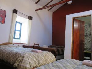 1 dormitorio con 2 camas y espejo en El Mirador del Inka Hostel en Cuzco