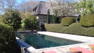 a swimming pool in front of a house at Haras de la Valterie in Saint-Hymer