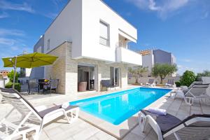 a villa with a swimming pool and patio furniture at Apartment Laura in Privlaka