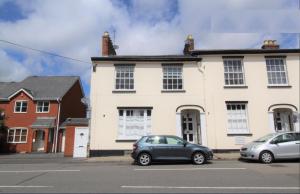 two cars parked in front of a white house at Velvet Nest 5 min walk from train station in Leamington Spa