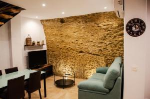 - un salon avec un mur en pierre et un canapé vert dans l'établissement Casa Cueva El Arrabal, à Setenil de las Bodegas