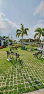 a park with benches and palm trees on the grass at Little Live in Harmony - Santiago in Santiago de los Caballeros