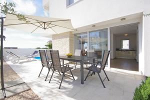 a patio with a black table and chairs and an umbrella at Apartment Laura in Privlaka
