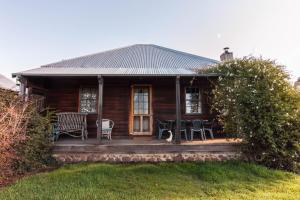 a wooden house with a porch with a table and chairs at Brickendon in Longford