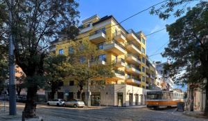 a bus is parked in front of a yellow building at Apartment City View in Sofia