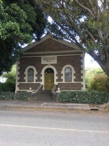 a small brick building with a yellow door at Angaston Masonic Lodge in Angaston