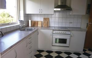 a kitchen with white cabinets and a stove and a sink at Holiday Home Korsbjerg in Allinge