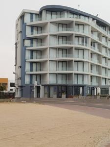 a large building on the beach next to the sand at Bayview Suites, Unit 9, Room # 13 in Langstrand
