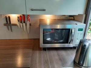 a microwave oven sitting under a cabinet in a kitchen at Boshuis Turquoise / smaakvol genieten op de Veluwe in Hoenderloo