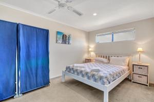 a bedroom with a bed with blue curtains and a window at Zephyr Shores - Port Willunga - C21 SouthCoast Holidays in Port Willunga