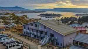 a house with a boat on the water at Alpine Resort Motel in Jindabyne