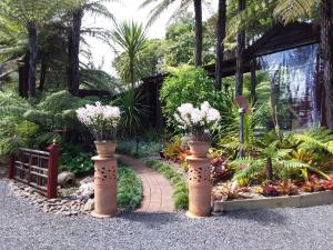 un jardín con dos jarrones con flores en Bali Haven, en Coromandel