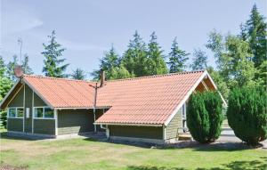 エーベルトフトにあるBeautiful Home In Ebeltoft With Saunaの赤屋根と木々二本の小屋